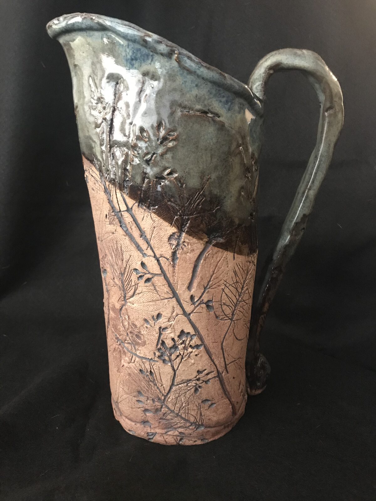 Tall hand-built pitcher with botanical impressions and slate blue glaze over textured raw clay