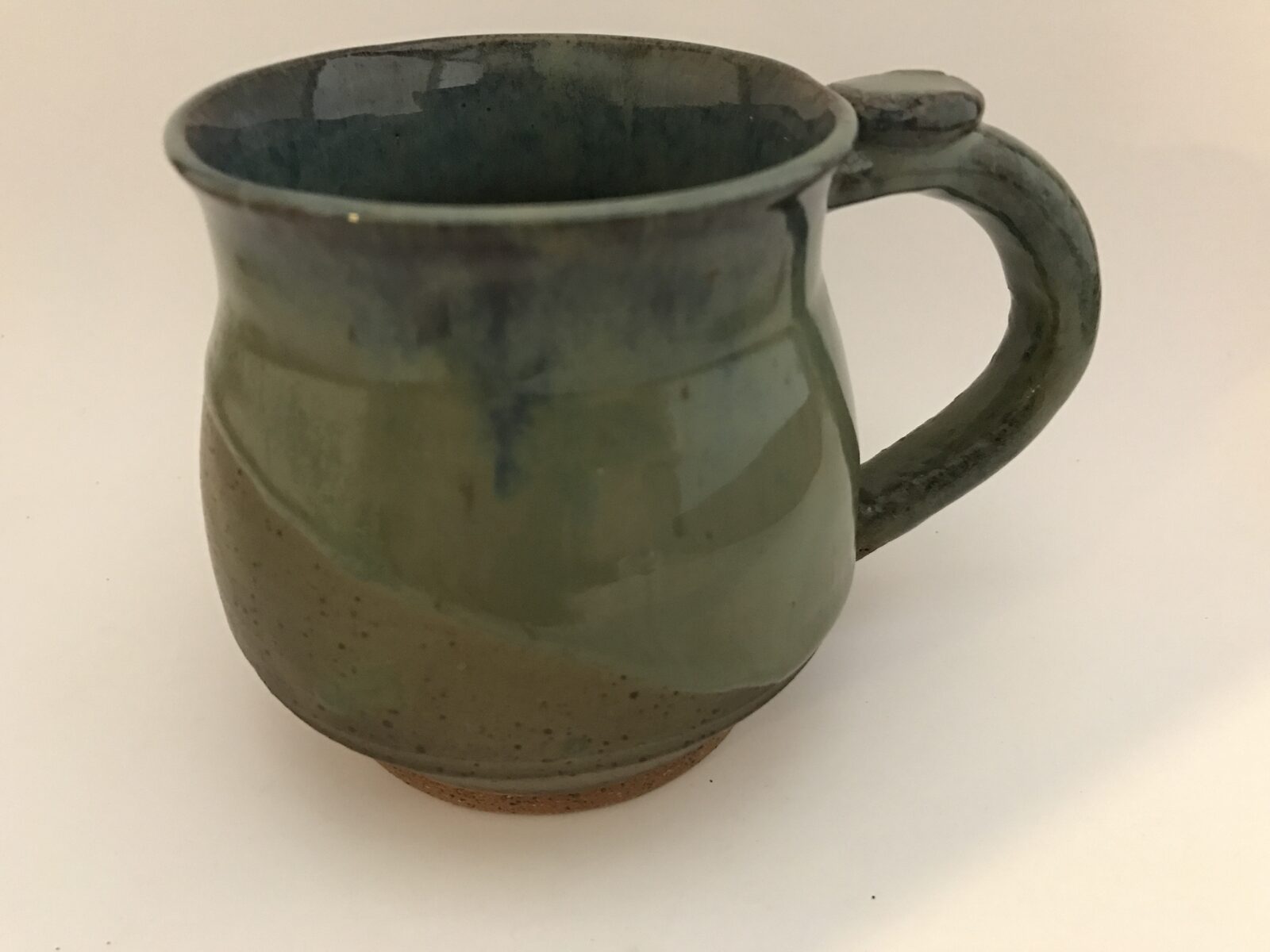 Round-bellied mug with green and blue glaze, exposed clay foot