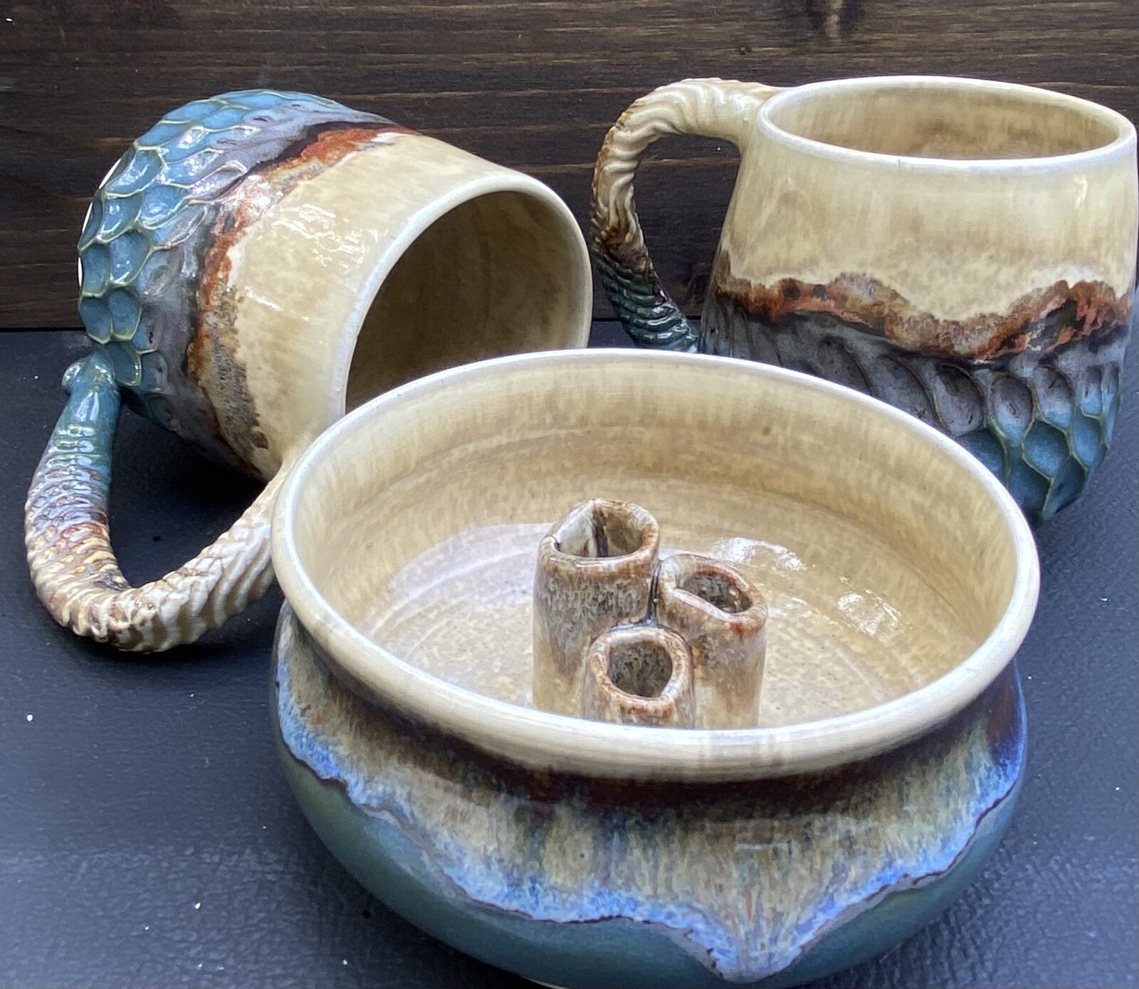 Two textured mugs with twisted handles and a candle holder bowl with three small posts