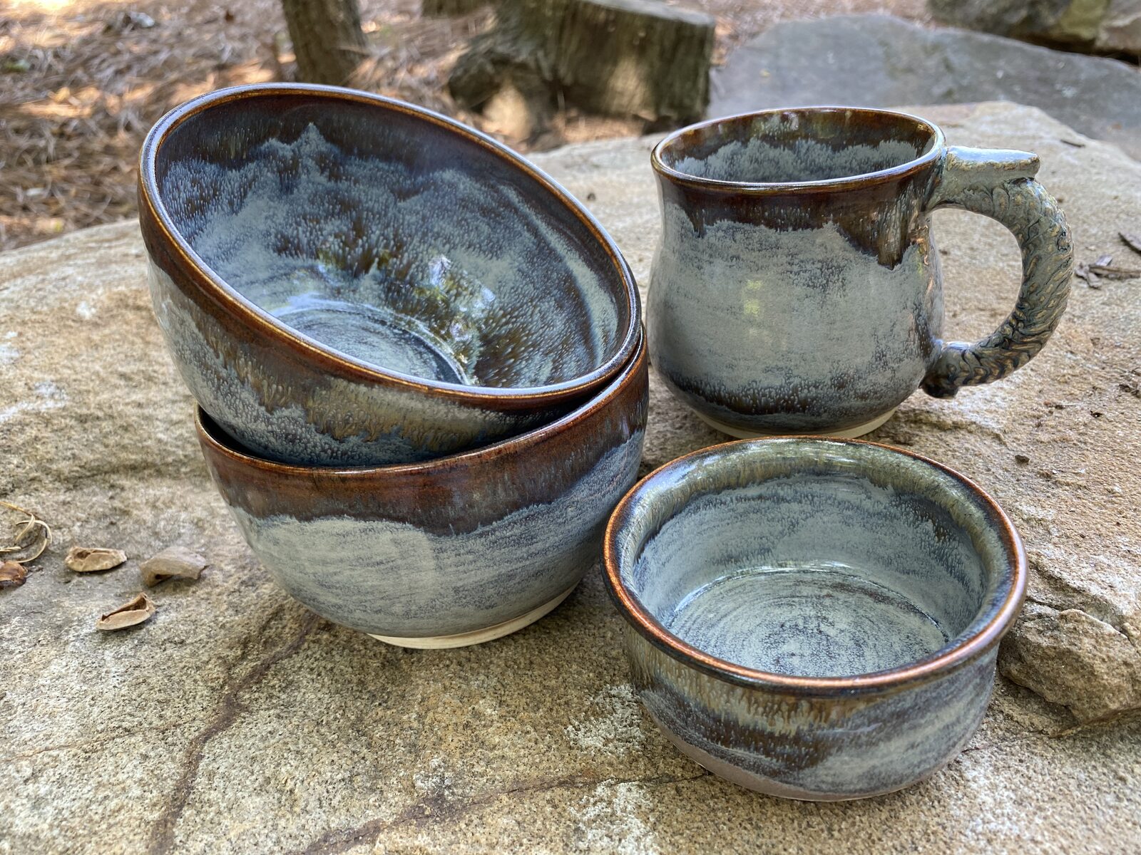 Matching set of bowls and a mug with twisted handle, copper-rimmed gray glaze