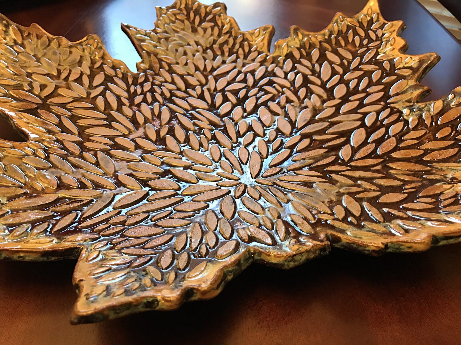 Large maple-leaf-shaped serving platter with intricate textured leaf patterns in amber and gold glaze